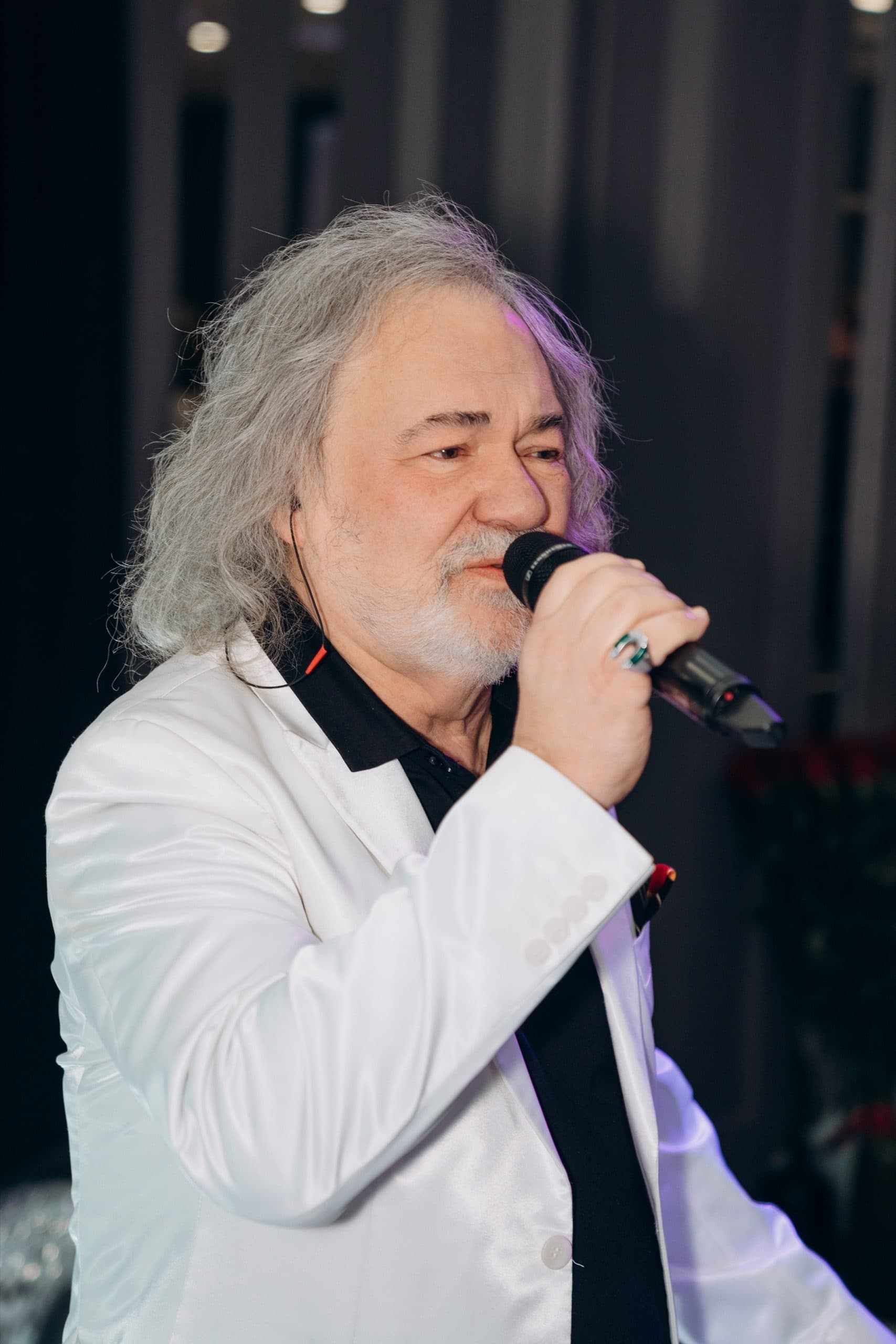 Співак у білому піджаку виконує пісню для гостей